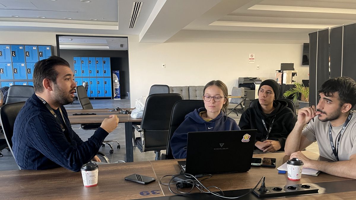 Mentor üç gence masada anlatıyor, dizüstü açık